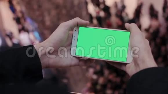 男性手使用智能手机与绿色屏幕在购物中心很多人在后台视频的预览图