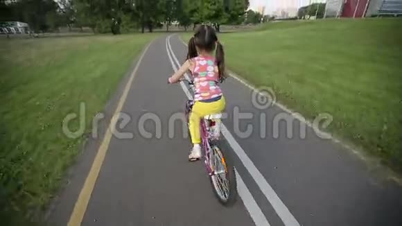 小女孩骑着粉红色的自行车在公园里骑自行车视频的预览图