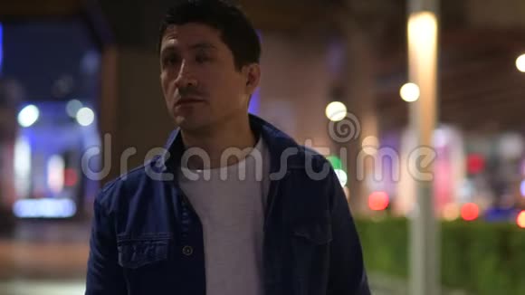 西班牙裔男子在夜间探索城市街道时思考视频的预览图