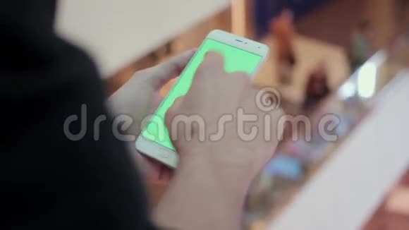 男性手使用智能手机与绿色屏幕在购物中心很多人在后台视频的预览图
