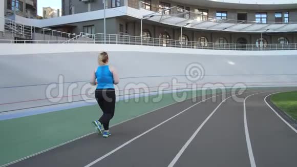 超重女性在城市体育场跑道上慢跑视频的预览图