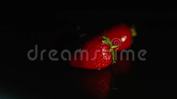 黑色背景下的新鲜草莓在黑暗中视频的预览图