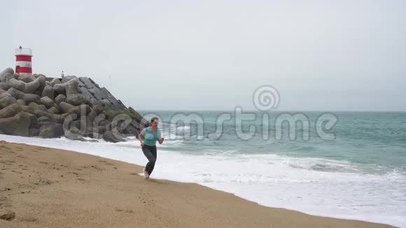 运动的女人沿着海滩奔跑慢动作视频的预览图