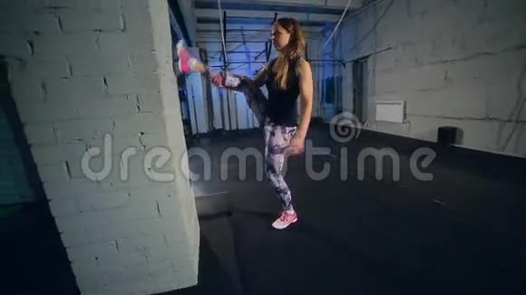 漂亮的肌肉女孩穿着灰色紧身裤做伸展运动工业风格的体育馆视频的预览图