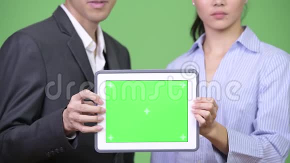 年轻的亚洲商界夫妇一起展示数码平板电脑视频的预览图