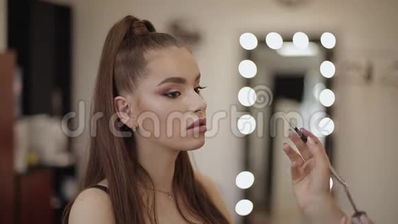 化妆师涂口红手的化妆师画唇的年轻美女红头模特在编视频的预览图