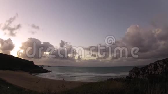 带着岩石沙子海浪和快速移动的云的海滩的延时镜头视频的预览图