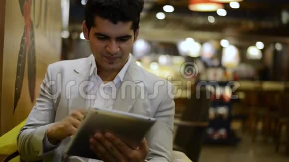 一个商人坐在咖啡馆里用数码平板电脑视频的预览图