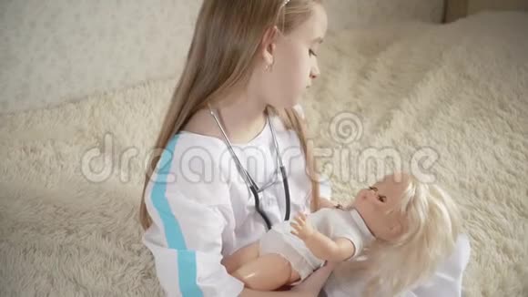 漂亮的小女孩在家里和娃娃玩医生视频的预览图