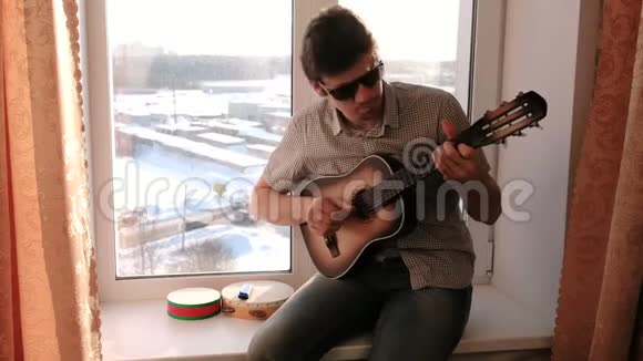 演奏乐器男人坐在窗台上弹吉他视频的预览图