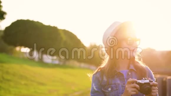 女孩正在绕着城市走来走去拍摄大自然的照片并在摄像机上观看风景视频的预览图