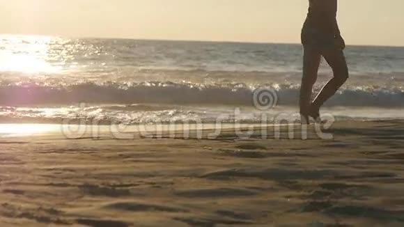 年轻女子踩着沙子靠近在沙滩上金色沙滩上散步的女游客海浪在视频的预览图