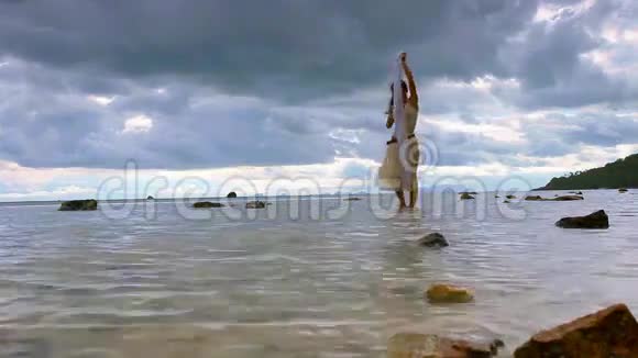 美丽的女人在海上戴着白色面纱行走视频的预览图