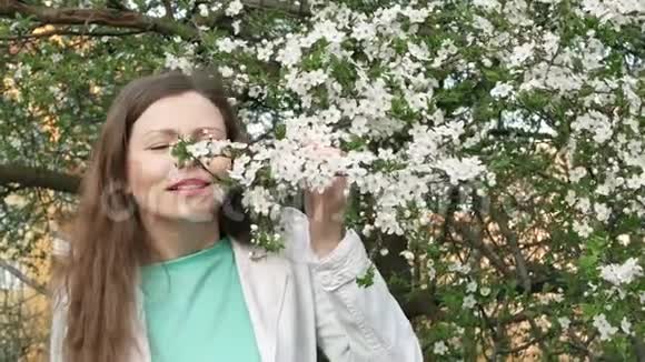 一位穿着白色夹克的美女在白花树上的户外画像视频的预览图