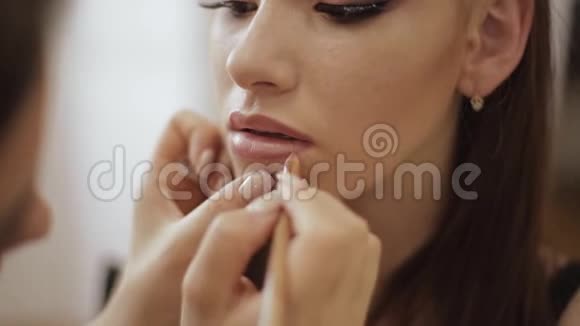 化妆师涂口红手的化妆师画唇的年轻美女红头模特在编视频的预览图
