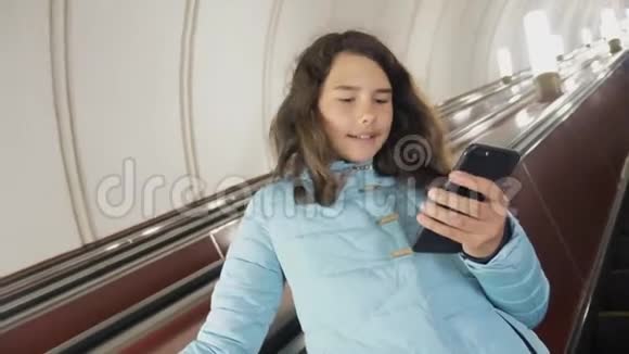 少女在地下地铁乘坐自动扶梯手持智能手机生活方式小女孩黑发女儿视频的预览图