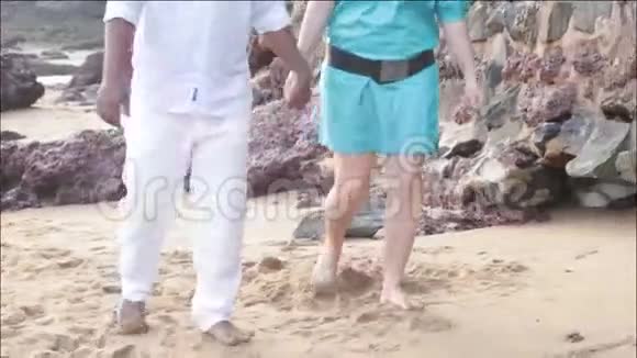 一个男人和一个女人在海滩上的沙滩上穿墙视频的预览图