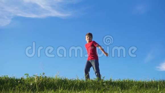 快乐的男孩在蓝天的绿色草地上跳跃视频的预览图