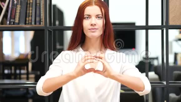 室内青年妇女亲手制作的心脏标志视频的预览图