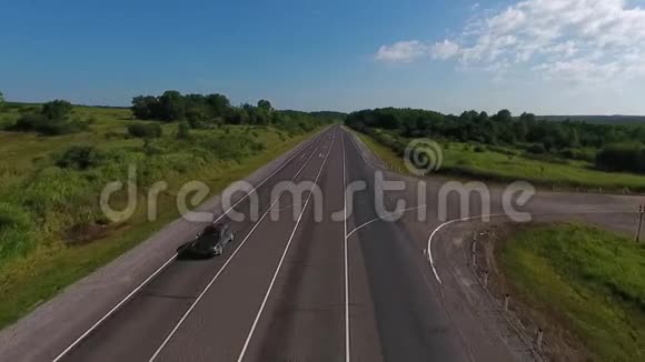 阳光明媚的一天汽车沿着空旷的乡村道路行驶上面的鸟瞰图视频的预览图