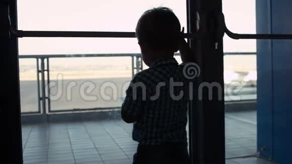 在机场透过窗户看的小男孩视频的预览图