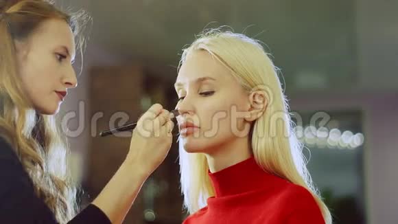 年轻女子在美容院给模特化妆视频的预览图