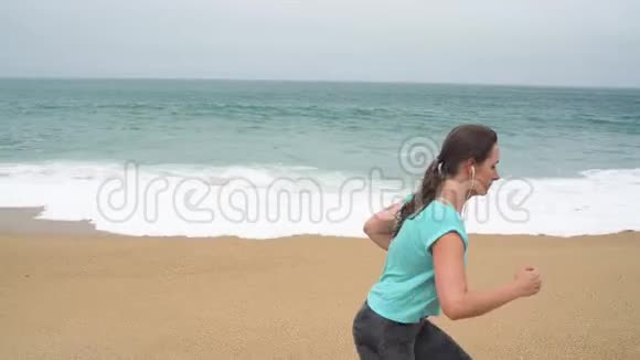 运动的女人沿着海滩奔跑慢动作视频的预览图