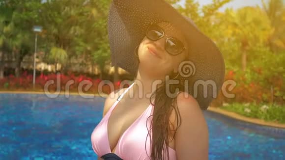 游泳池边戴蓝帽子的漂亮女孩夏日的阳光慢动作视频的预览图