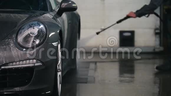 汽车服务部门的工人正在用水管把一辆豪华轿车冲洗干净视频的预览图