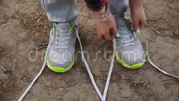 小女孩在户外散步停下来把鞋带系在运动鞋上视频的预览图