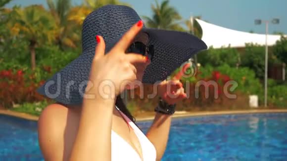 游泳池边戴蓝帽子的漂亮女孩夏日的阳光慢动作视频的预览图