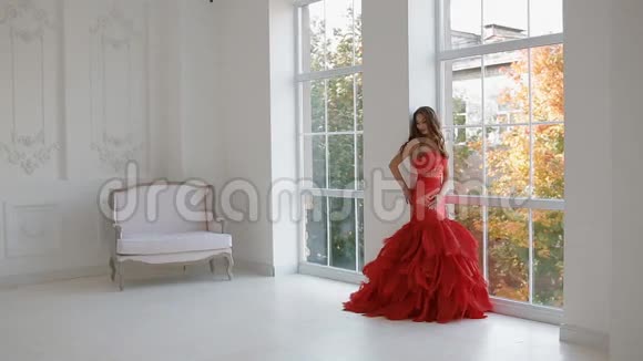 一个穿着红色裙子在工作室摆姿势的女强人视频的预览图