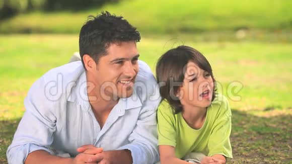 男人和他的儿子躺在草地上视频的预览图