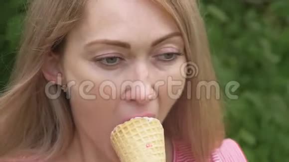 女人舔冰淇淋女孩在舔一个美味的奶油冰淇淋有草莓味的冰淇淋甜筒视频的预览图