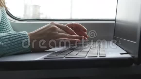 女性手在火车上的笔记本电脑键盘上打字女人在铁路上旅行时和朋友聊天少女视频的预览图