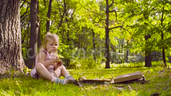 小女孩坐在公园里吃披萨视频的预览图