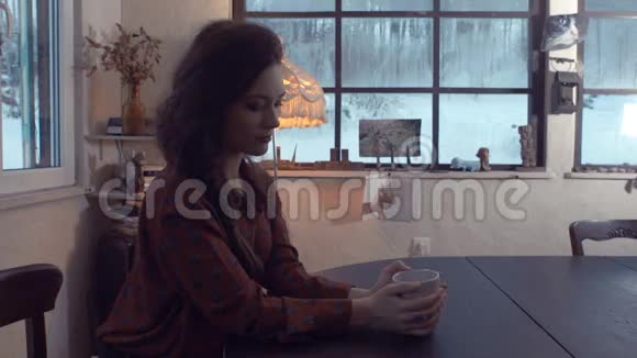 年轻女子坐在一张桌子旁端着一杯茶视频的预览图