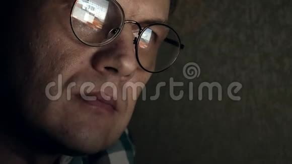 戴眼镜的人工作到深夜他看起来很担心他在面前的电脑屏幕上看到一个特写镜头视频的预览图
