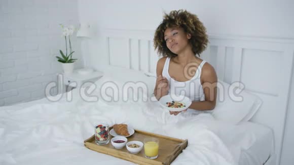 知足的女人在床上吃早餐视频的预览图