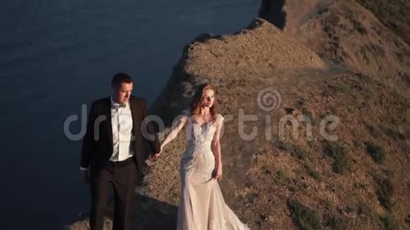 新郎新娘日落时分在山上散步视频的预览图