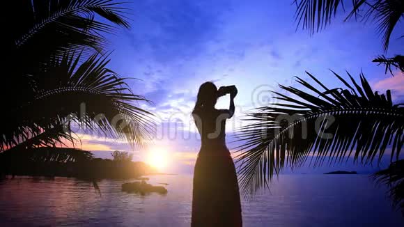 女人在日落时通过电话拍照视频的预览图