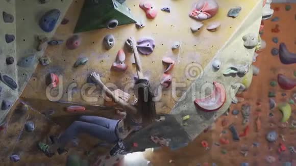 年轻女子攀岩者正在攀岩健身房里攀岩苗条美丽的女人在室内攀岩墙上锻炼视频的预览图