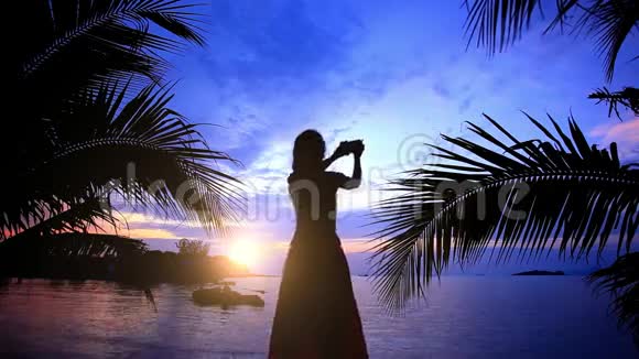 女人在日落时通过电话拍照视频的预览图