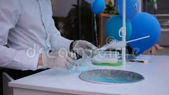 一个年轻人在一台特殊的机器上做棉花糖上面系着蝴蝶结身后放着气球视频的预览图