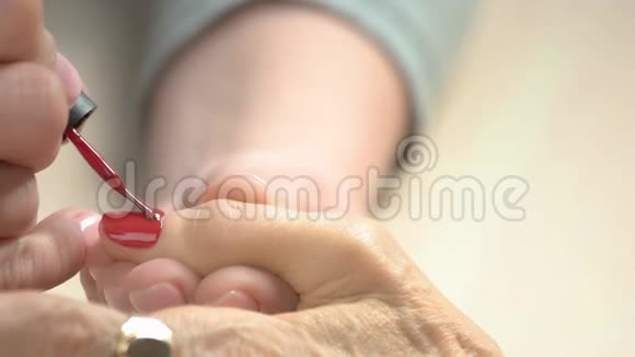 医生给年长的女人涂红清漆视频的预览图