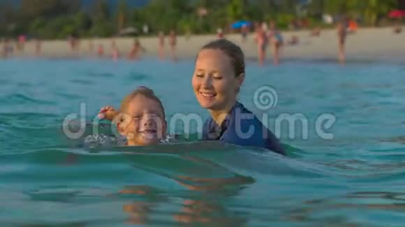 女子游泳教练教小男孩在日光浴时在海里游泳视频的预览图
