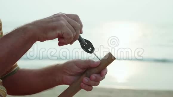 老人坐在海滩上用手制作长笛特写视频的预览图