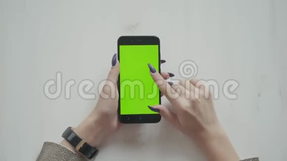 美丽的女孩手里拿着智能手机手里拿着绿色的屏幕视频的预览图