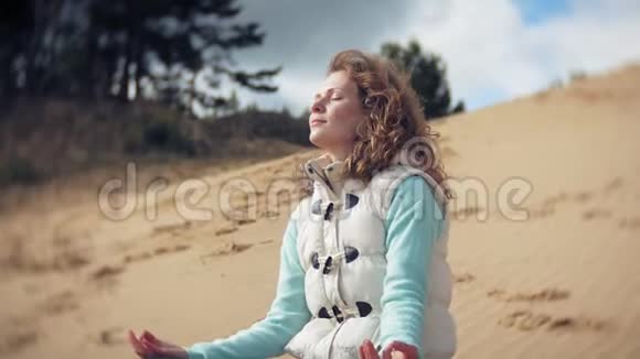 女人坐在靠近水面的沙滩上摆出一个莲花瑜伽姿势视频的预览图