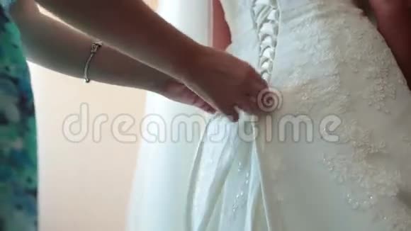 新娘在婚纱上系扣子视频的预览图